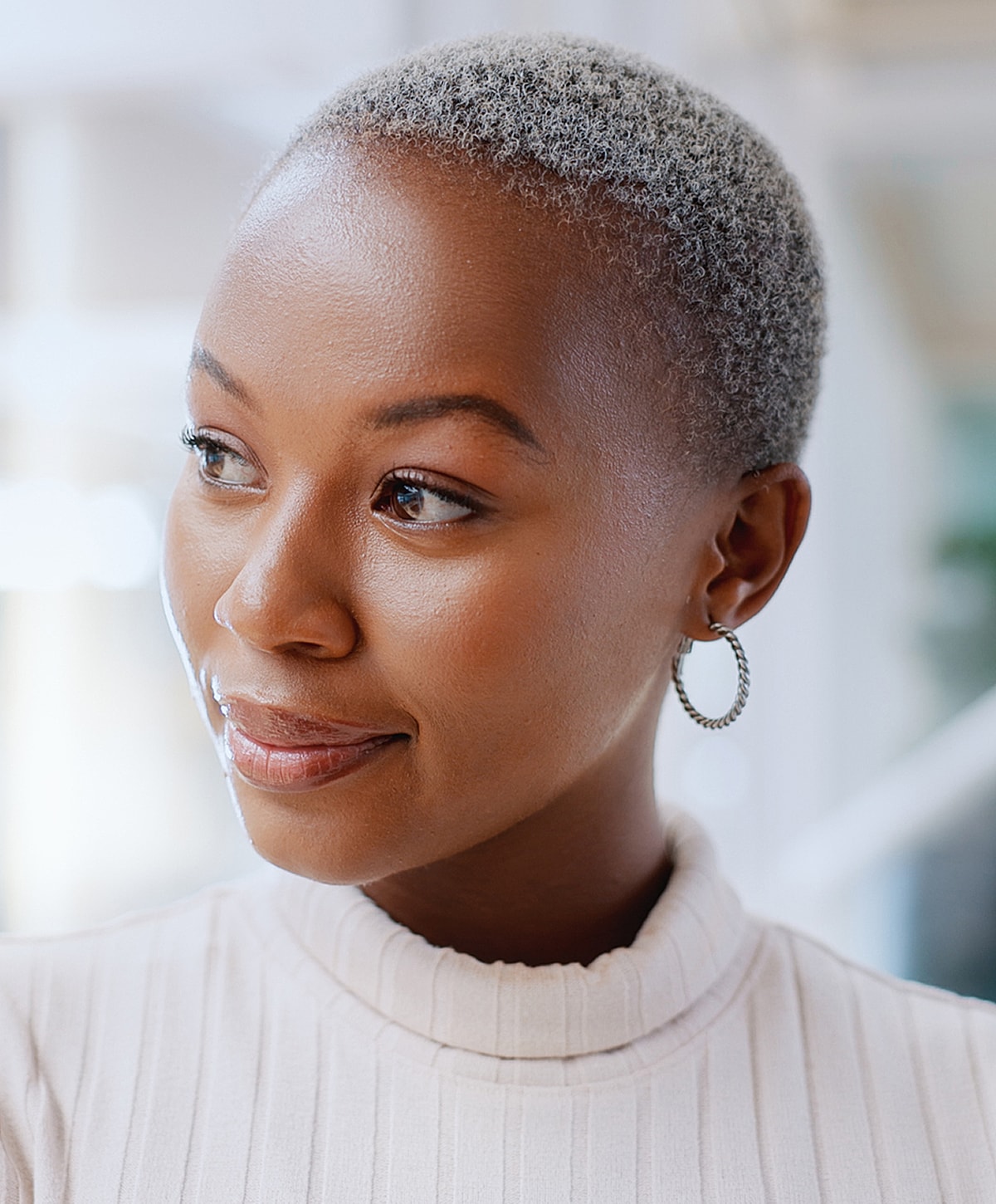 Woman with cropped hair and elegant earrings.